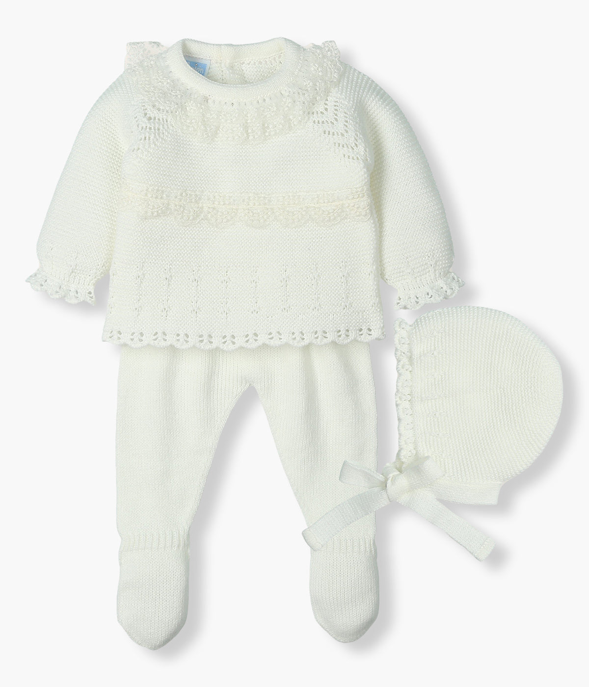 Conjunto de 3 peças em malha pérola da Mac Ilusión composto por camisola, calças e touca para bebé menina e recém-nascida. Camisola com gola folho e detalhes em renda com malha detalhada. Touca com pequeno rebordo. Calças com pés.