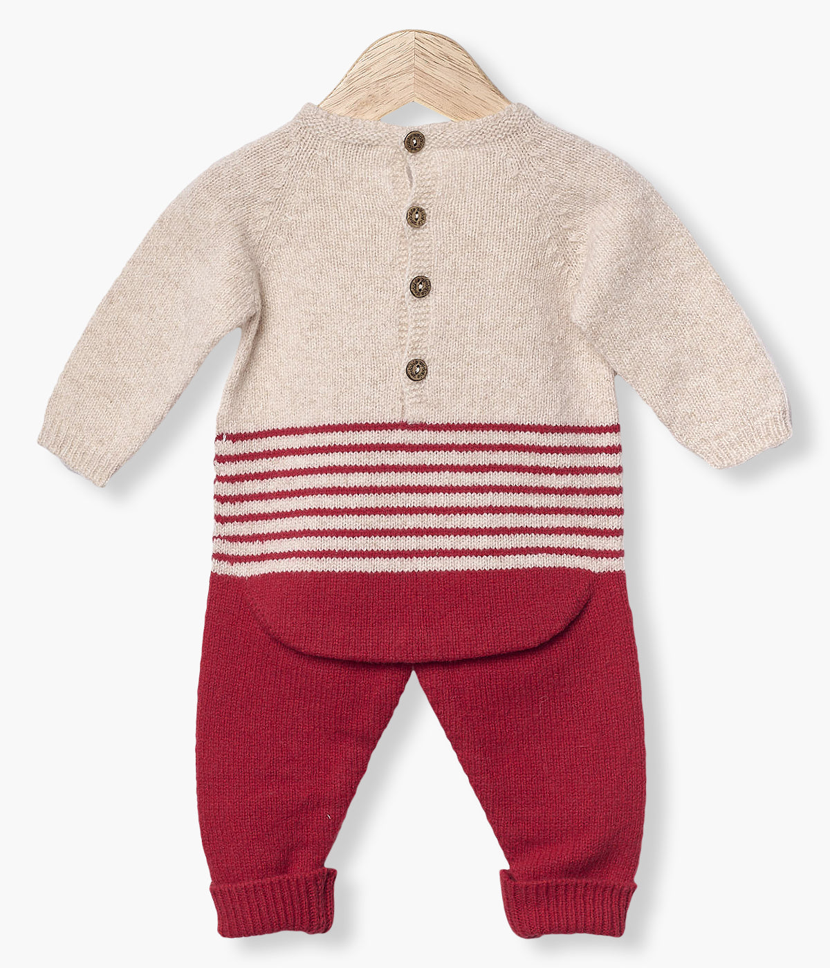 Babygrow tricotado em lã merino da Wedoble para bebé e recém-nascido(a). Parte superior em bege e parte inferior com riscas em vermelho. Abertura nas costas com botões de madeira e entrepernas com molas de pressão para vestir facilmente.