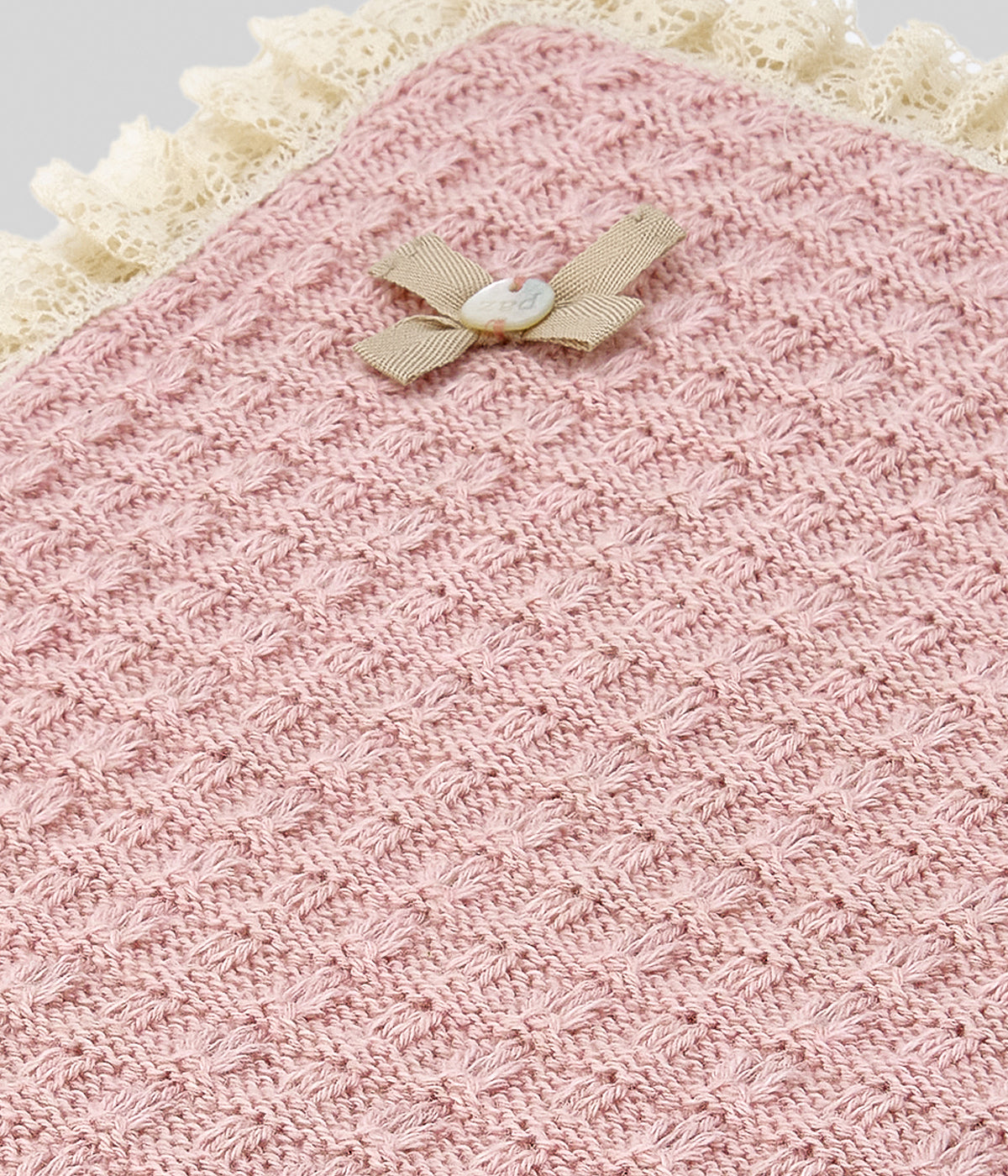 Manta em malha de algodão com caxemira rosa-velho da Paz Rodríguez para bebé menina e recém-nascida. Suave manta de formato quadrado com renda detalhada a toda a volta, detalhes com relevo e medalha madrepérola com pequeno laço.