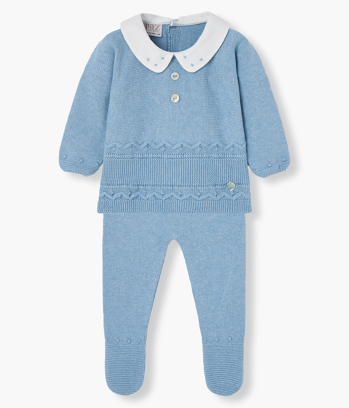 Conjunto de 2 peças em malha de algodão com caxemira azul da Paz Rodríguez para bebé menino e recém-nascido. Camisola com gola redonda cortada branca com bordado pintas azuis, dois botões madrepérola decorativos, detalhes na malha e medalha da marca. Calças com pés detalhados a combinar com a camisola.