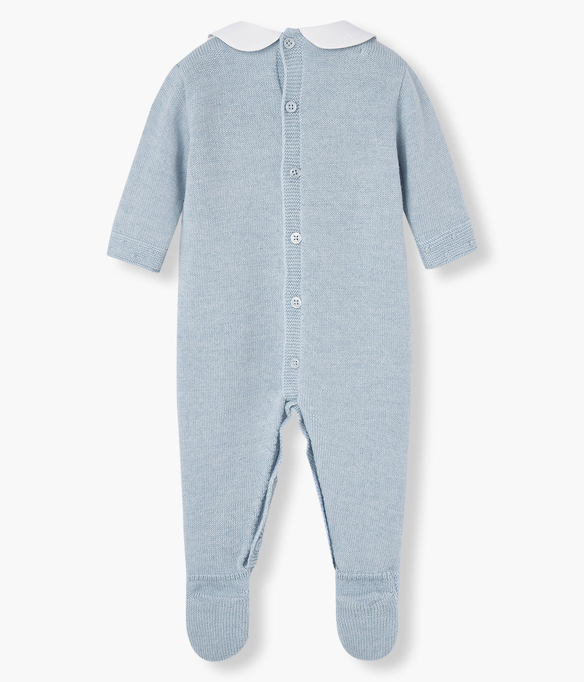 Babygrow em malha azul da Paz Rodríguez para bebé e recém-nascido(a). Elegante babygrow com gola redonda cortada branca, detalhes na malha no peito e nos pés e medalha da marca.
