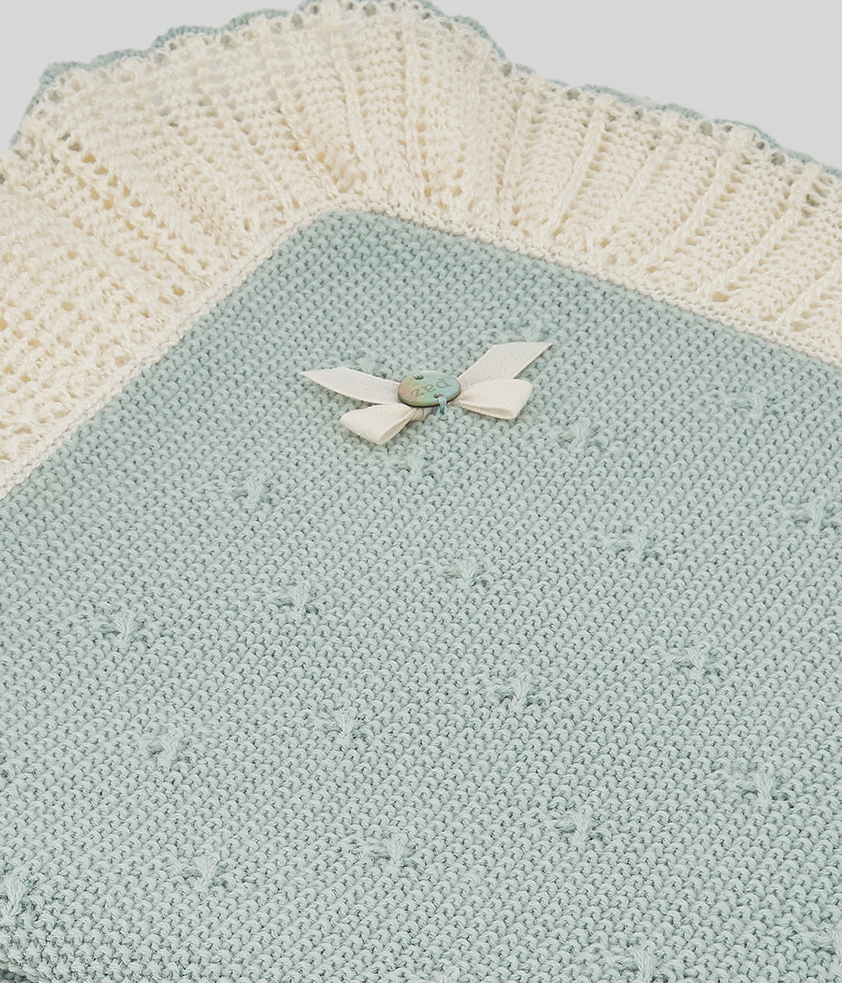 Manta de malha verde-água da Paz Rodríguez para bebé menina e recém-nascida. Elegante manta de formato quadrado com rebordo ondulado perfurado em pérola, detalhes na malha e medalha com laço.