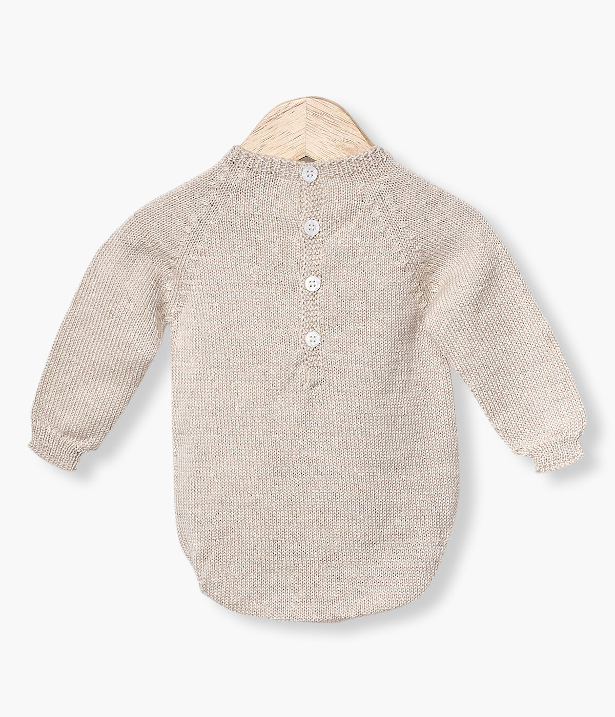 Fofo tricotado em lã merino bege da Wedoble para bebé e recém-nascido(a). Suave fofo com detalhes entrelaçados na malha de abertura nas costas e entrepernas.