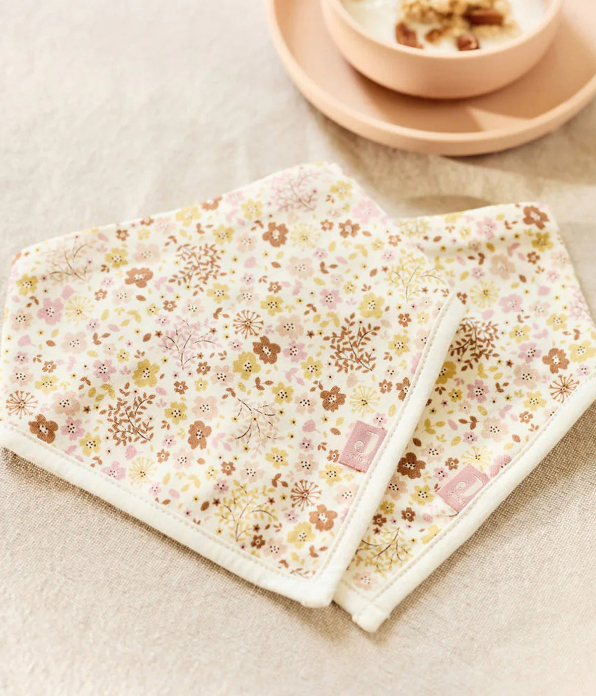 Pack composto por duas babetes estilo bandana em algodão pérola com padrão floral em tons de rosa e bege para bebé menina e recém-nascida. Fecho com molas de pressão em duas medidas.