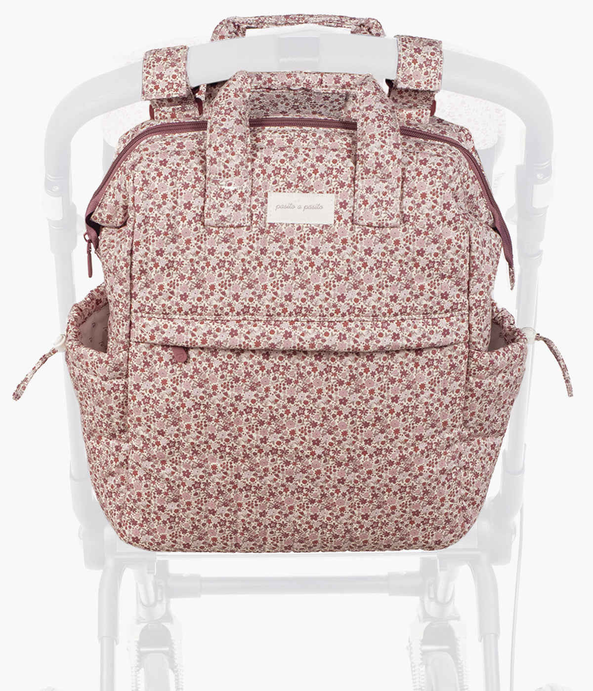 Mochila de maternidade Cherry Flowers da Pasito a Pasito pendurada no carrinho de bebé.