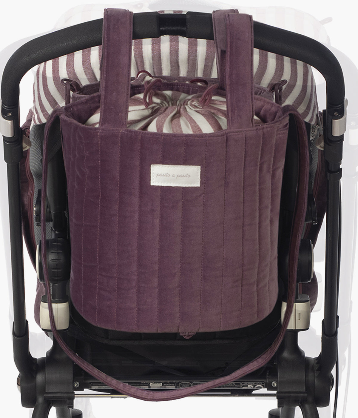 Bolsa Bucket Pasito a Pasito Cherry Velvet com um elegante exterior em veludo de algodão impermeável em tons de bordô. O seu formato tipo balde maximiza o espaço interior, permitindo uma organização prática e um acesso rápido aos essenciais do(a) bebé.