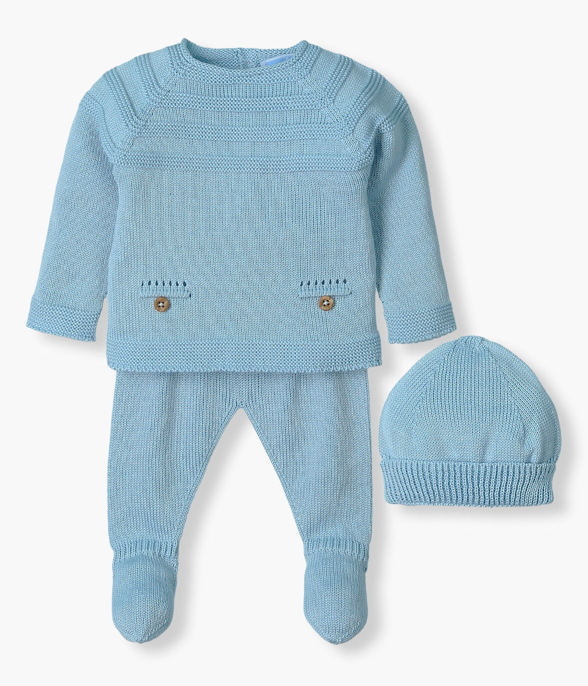 Conjunto de 3 peças em malha azul da Mac Ilusión composto por camisola, calças e gorro para bebé e recém-nascido(a). Camisola com nervuras com relevo e dois bolsos decorativos com botões de madeira. Calças com pés e gorro liso com dobra.
