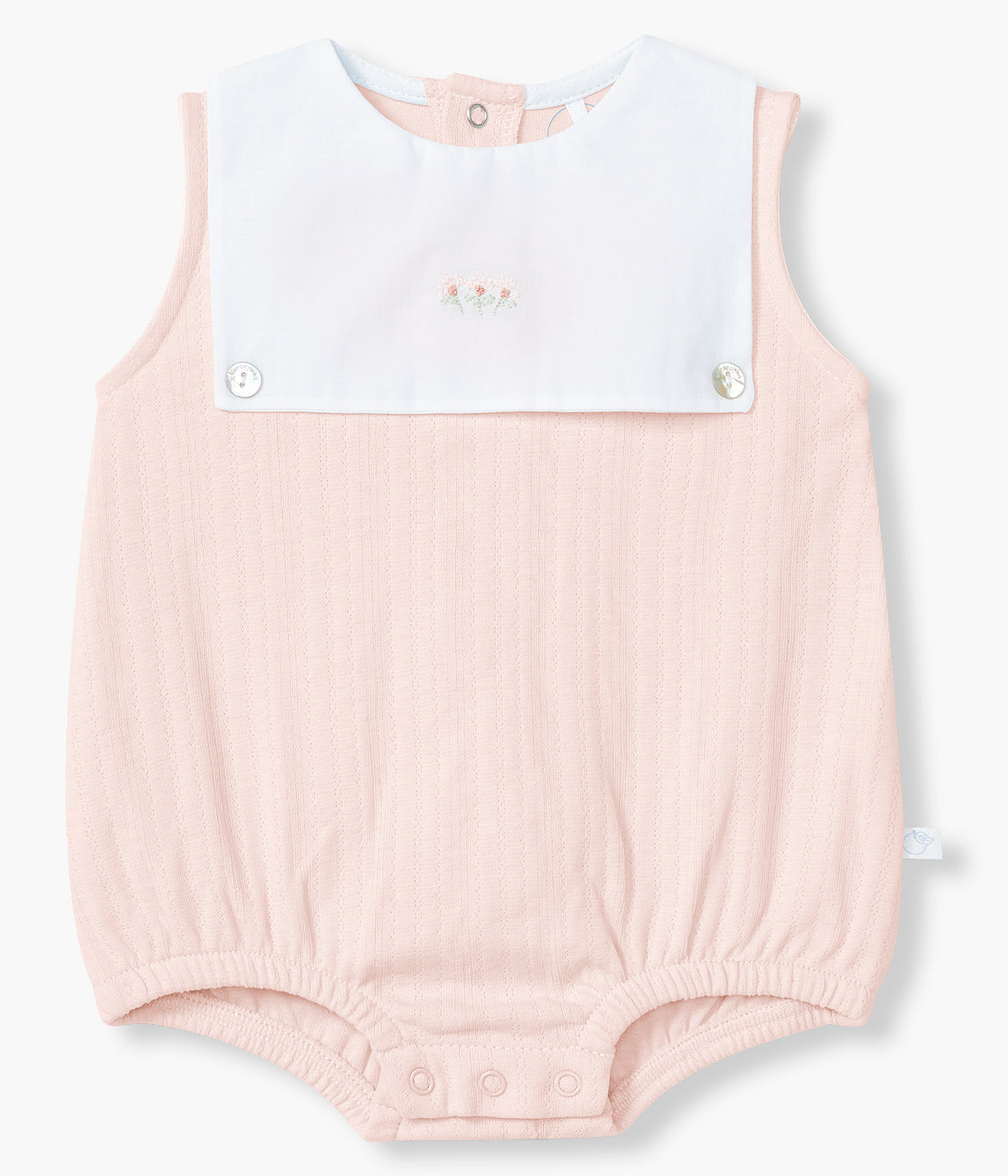 Vista de frente do fofo em algodão rosa da Laranjinha para bebé menina e recém-nascida. Delicado fofo de manga cava com peitilho em tecido branco com flores bordadas e dois botões madrepérola decorativos. Aberturas nas costas e entrepernas.