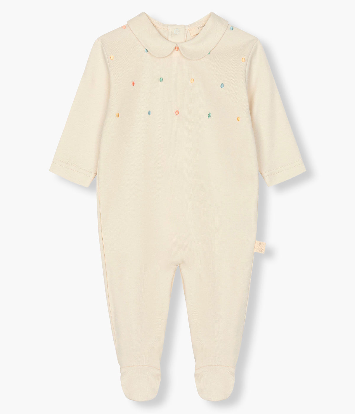 Vista de frente do babygrow em algodão bege da Baby Gi para bebé e recém-nascido(a). Gola redonda cortada e pintas coloridas bordadas no peito. Abertura com molas de pressão nas costas e entrepernas.