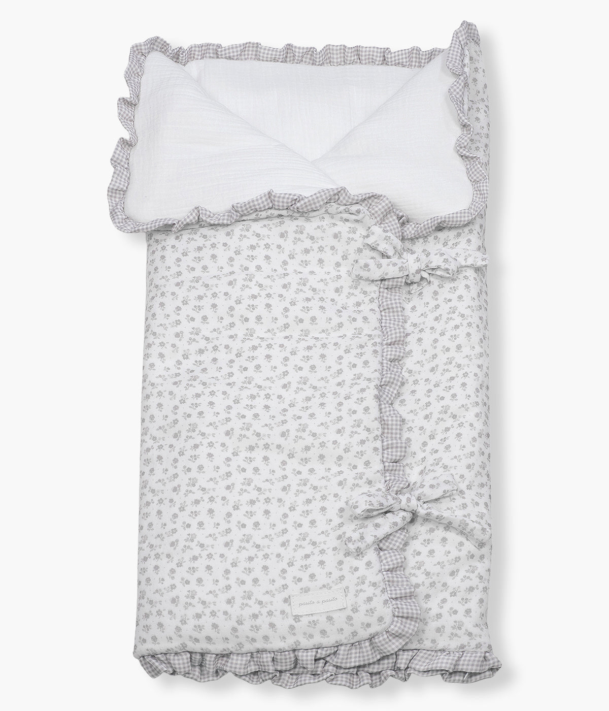 Vista de frente do saco manta Pasito a Pasito Little Bloom Flowers com clássico padrão floral em tons cinza. Feito em musselina de algodão e com um TOG de 2.5, este saco manta é ideal para a pele delicada do(a) recém-nascido(a). Possui um design funcional permitindo ser utilizado como ninho ou como manta de berço, acompanhando o crescimento e as diferentes necessidades do bebé.