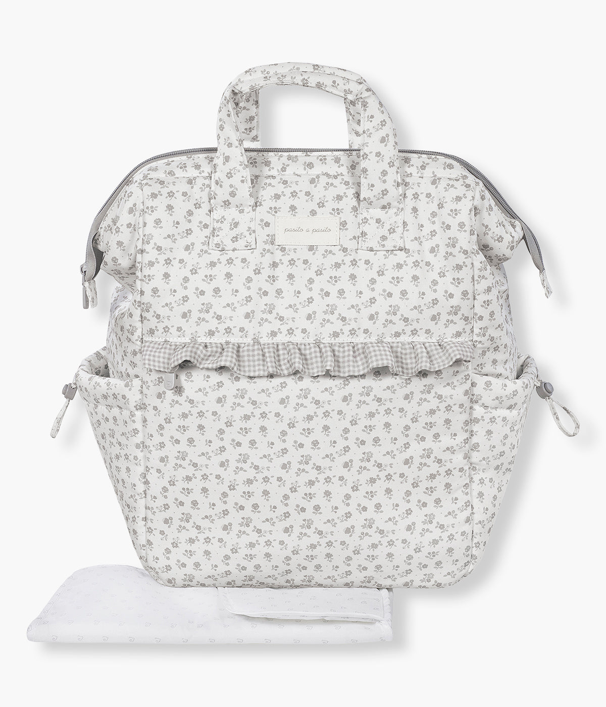 Vista de frente da mochila de maternidade Little Bloom Flowers da Pasito a Pasito. Com exterior em loneta de algodão resistente à água com padrão floral em tons de cinza, esta mochila de maternidade oferece grande capacidade, vários compartimentos e inclui um prático resguardo portátil.