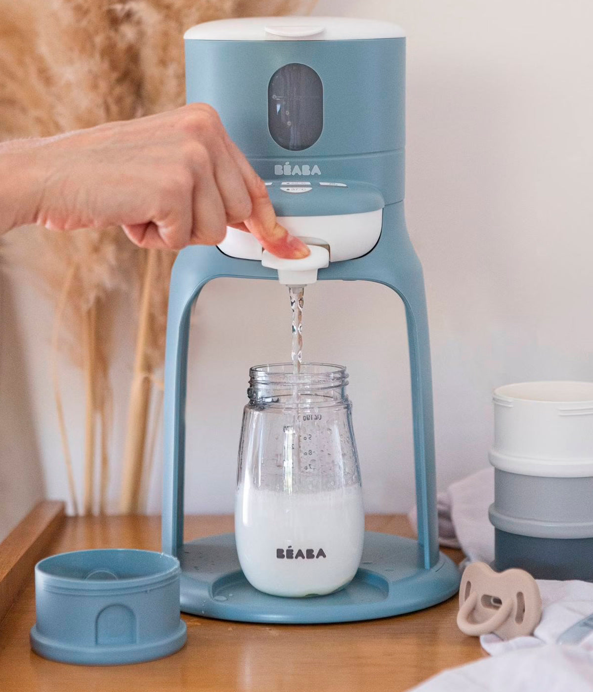 Vista frontal do aquecedor de água para biberões Bib'Expresso da Béaba na cor Baltic Blue (azul). Prático aparelho que aquece rapidamente a água à temperatura ideal em apenas 30 segundos, com funcionamento intuitivo e utilização com uma só mão, permitindo preparar biberões de forma simples e precisa. Inclui ainda função banho-maria para aquecer biberões já preparados e boiões de comida, num design compacto e fácil de transportar.