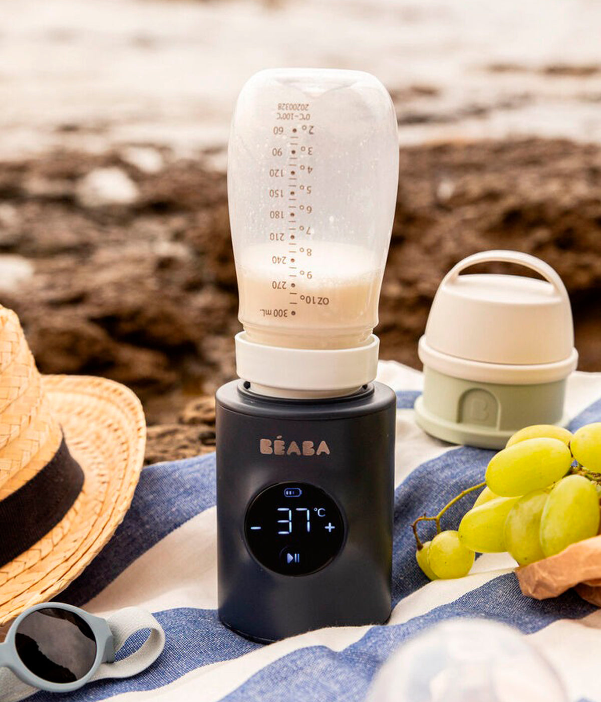Aquecedor de biberões portátil Milk Nomad da Béaba a ser utilizado na praia.