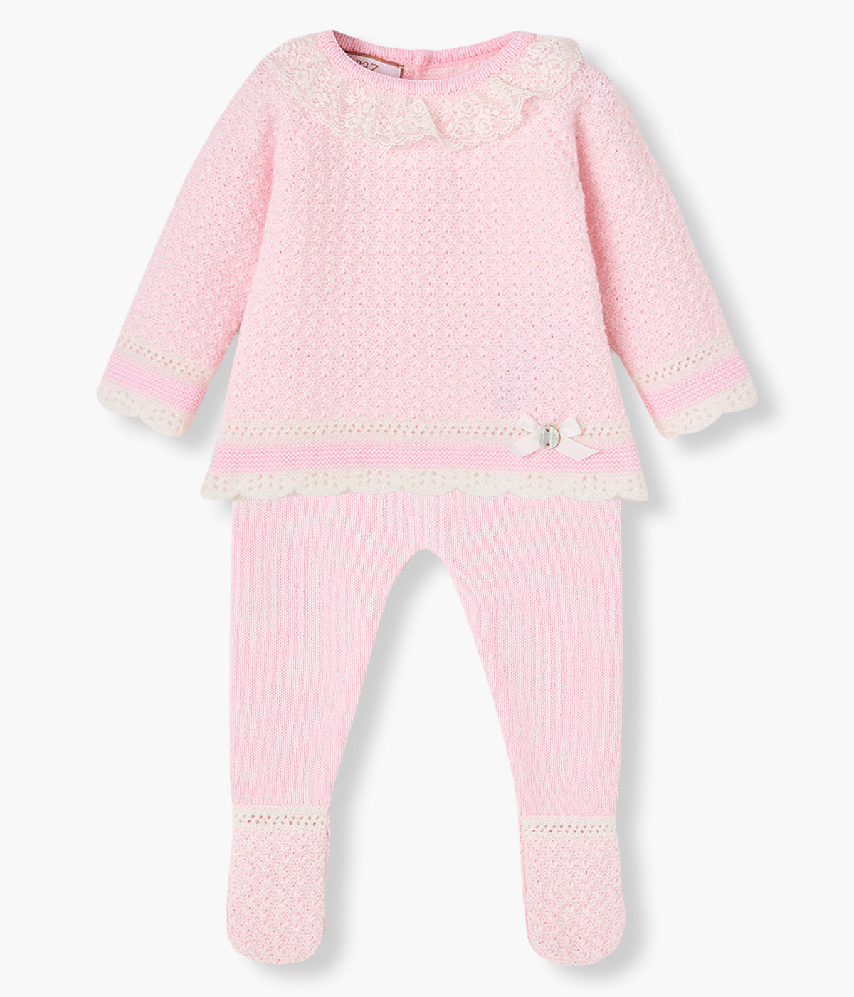 Vista frontal do conjunto de 2pc em malha rosa da Paz Rodríguez para bebé menina e recém-nascida. Camisola com gola folho em renda bege, detalhes com relevo e medalha de madrepérola com laço gorgurão. Calças com pés a combinar.
