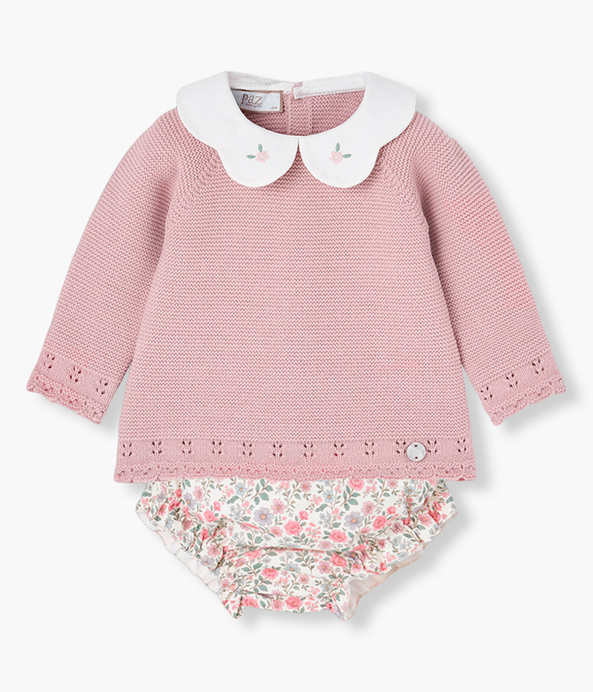 Vista frontal do conjunto da Paz Rodríguez composto por camisola e tapa fraldas para bebé menina e recém-nascida. Camisola com gola redonda cortada com flores bordadas e contornos detalhados. Tapa fraldas em algodão pérola com padrão floral e forro em tecido.