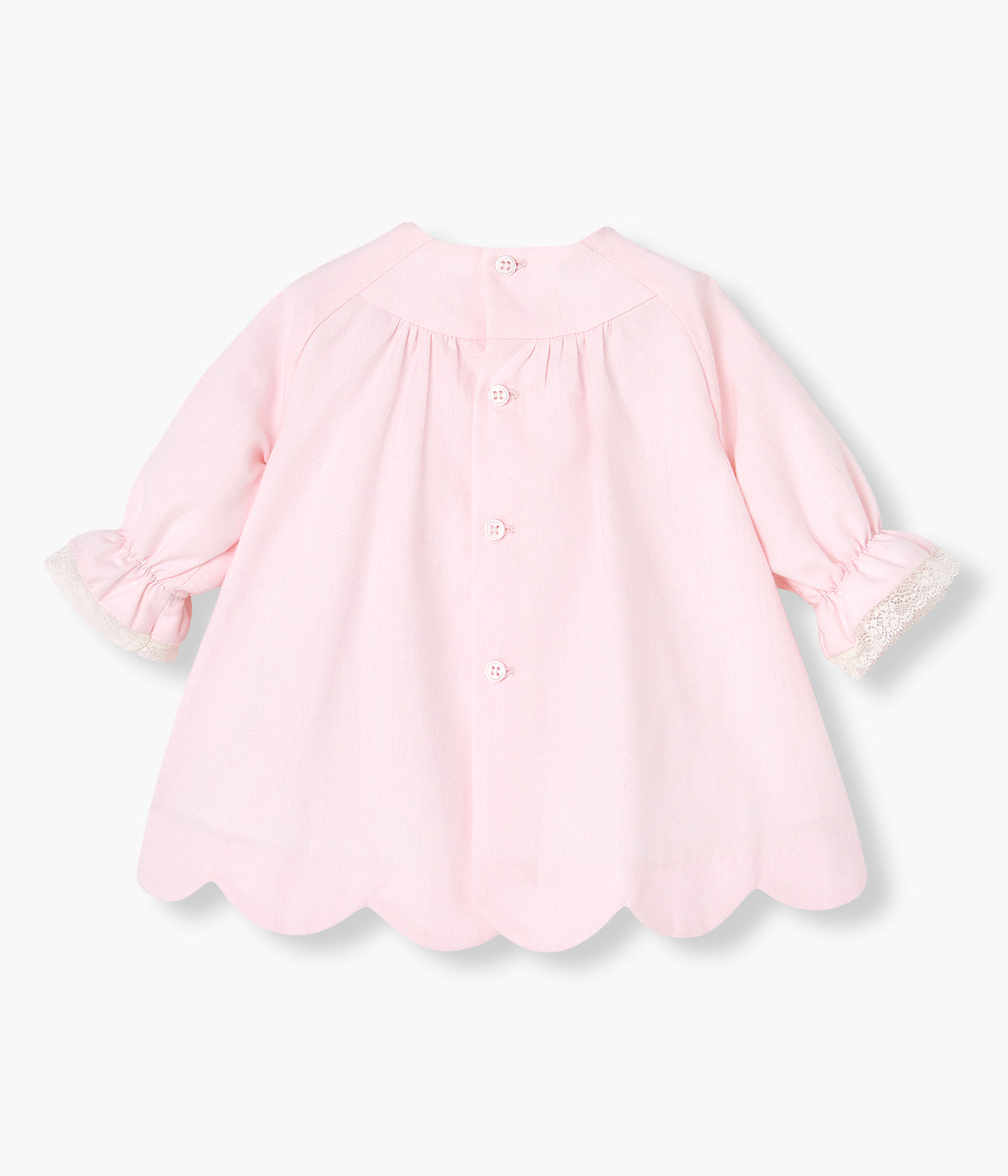 Vista costas do vestido com tapa fraldas em algodão da Paz Rodríguez para bebé menina e recém-nascida. Peito com detalhe em tecido e medalha de madrepérola com laço. Detalhes em renda no peito e nos punhos. Contorno inferior com efeito ondulado. Tapa fraldas a combinar.