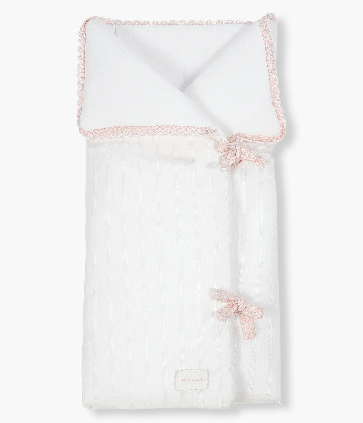 Vista frontal do saco Manta Maison Tender da Pasito a Pasito. Elegante saco manta com TOG 2.5 que proporciona uma envolvência suave e confortável nos primeiros meses da bebé. Fabricado em 100% algodão, combina um exterior branco com delicada textura de riscas verticais e um interior em musselina lisa de algodão. O formato tipo envelope, os laços de ajuste e o fecho de correr na zona dos pés ajudam a manter a bebé aconchegado, podendo ainda ser completamente aberto e utilizado como manta.