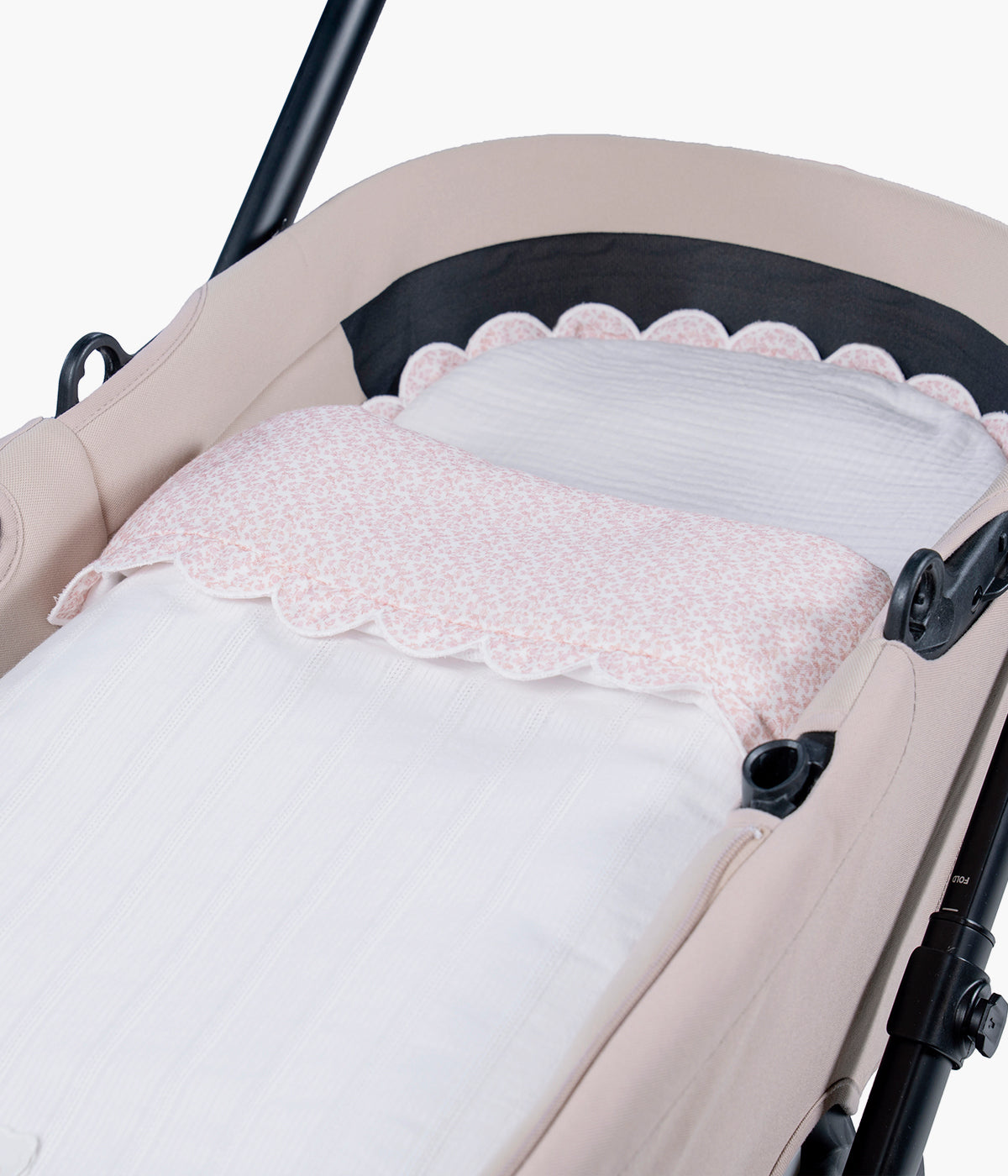 Vista detalhada do saco de dormir Maison Tender da Pasito a Pasito. Elegante saco manta com TOG 2.5 que proporciona um espaço suave, confortável e acolhedor para os primeiros passeios da bebé. Fabricado em 100% algodão, combina um exterior branco com delicada textura de riscas verticais e um interior em musselina de algodão com padrão flores rosa.