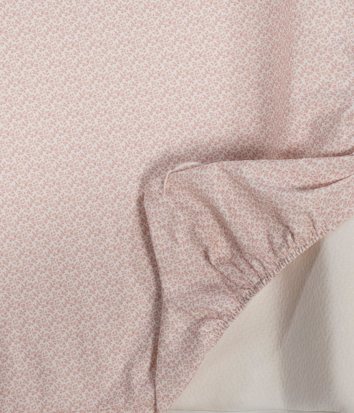 Vista detalhada do trocador de fraldas Maison Tender da Pasito a Pasito. Superfície confortável e estável para as trocas diárias da bebé com padrão flores rosa. Possui interior em espuma viscoelástica, capa impermeável e removível em 100% algodão e base antiderrapante para maior estabilidade. Com medidas de 70 × 50 cm, inclui ainda um pequeno muda-fraldas adicional e cumpre a norma EN 12221 para muda-fraldas de uso doméstico.