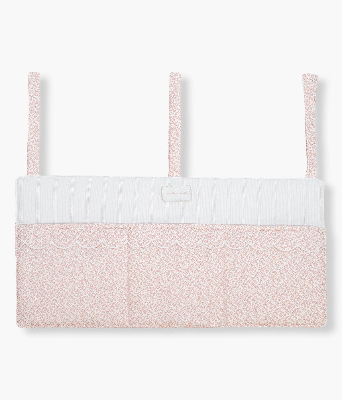 Vista frontal do organizador de berço Maison Tender da Pasito a Pasito com o padrão floral rosa. Perfeito para manter os essenciais da bebé sempre organizados e facilmente acessíveis junto ao berço. Fabricado em algodão, possui bolsos amplos e estruturados para fraldas, musselinas, chupetas e pequenos acessórios, fixando-se facilmente através de fitas ajustáveis. O delicado padrão de coelhinhos completa o ambiente com o estilo suave e elegante da coleção Maison Tender.