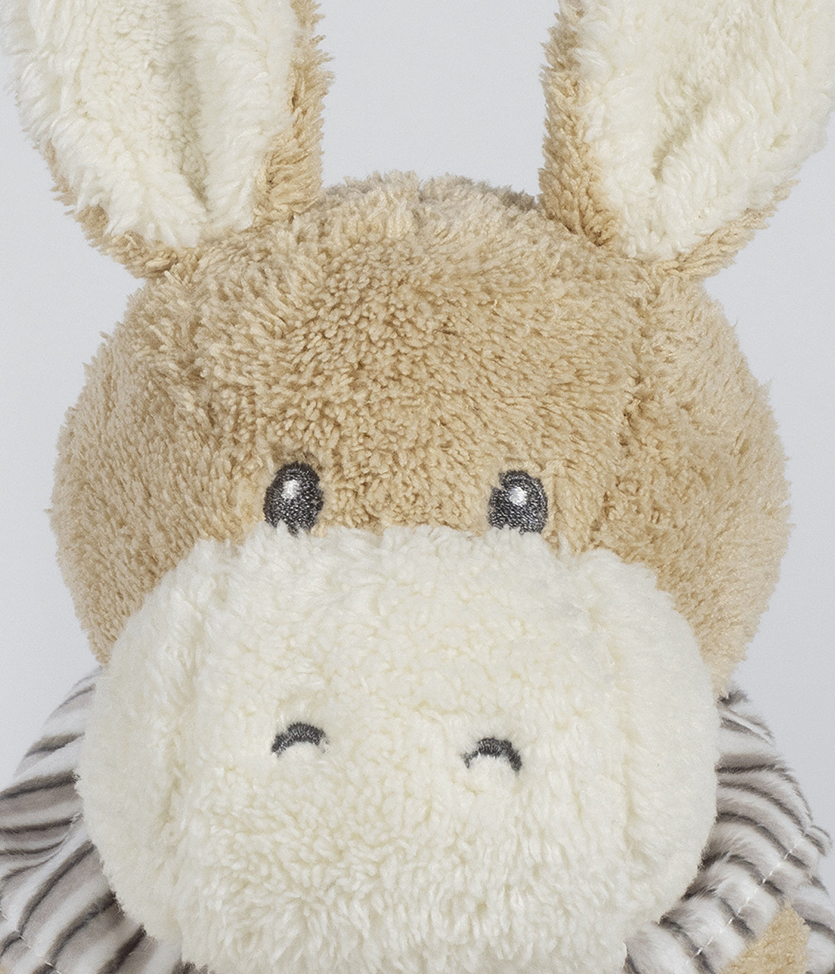 Peluche Walking Mum Botton Strips para bebé e recém-nascido com 27cm em forma de burro de cor bege com orelhas e focinho em pérola e roupa com padrão riscas em tons de cinza.