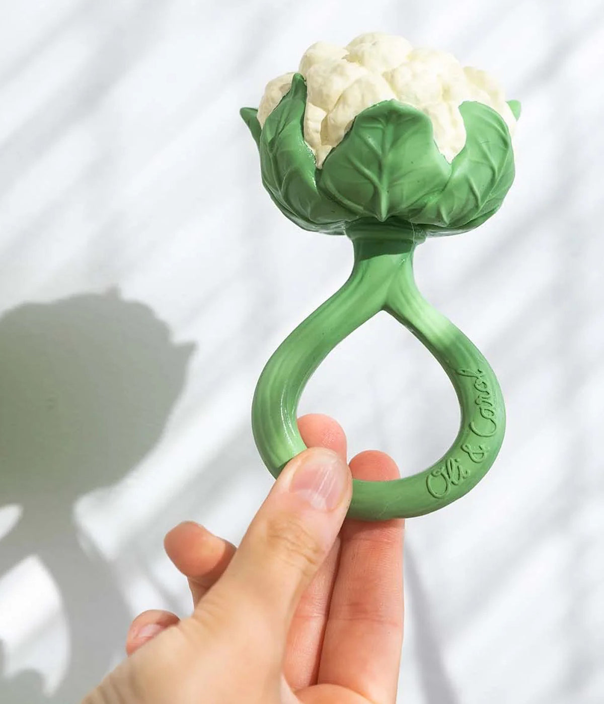 Mão a segurar no mordedor e chocalho em borracha natural para bebé Cauliflower da Oli&Carol.