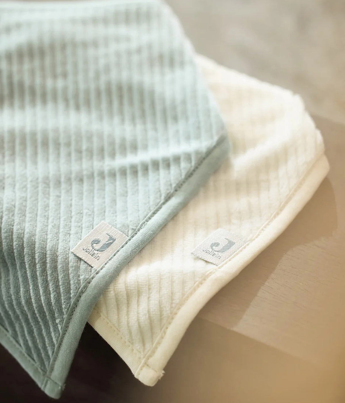 Conjunto de duas babetes em veludo canelado da Jollein para bebé e recém-nascido(a). Suaves babetes, uma pérola e outra azul, perfeitas para manter o bebé limpo enquanto aprende a beber e comer sozinho.