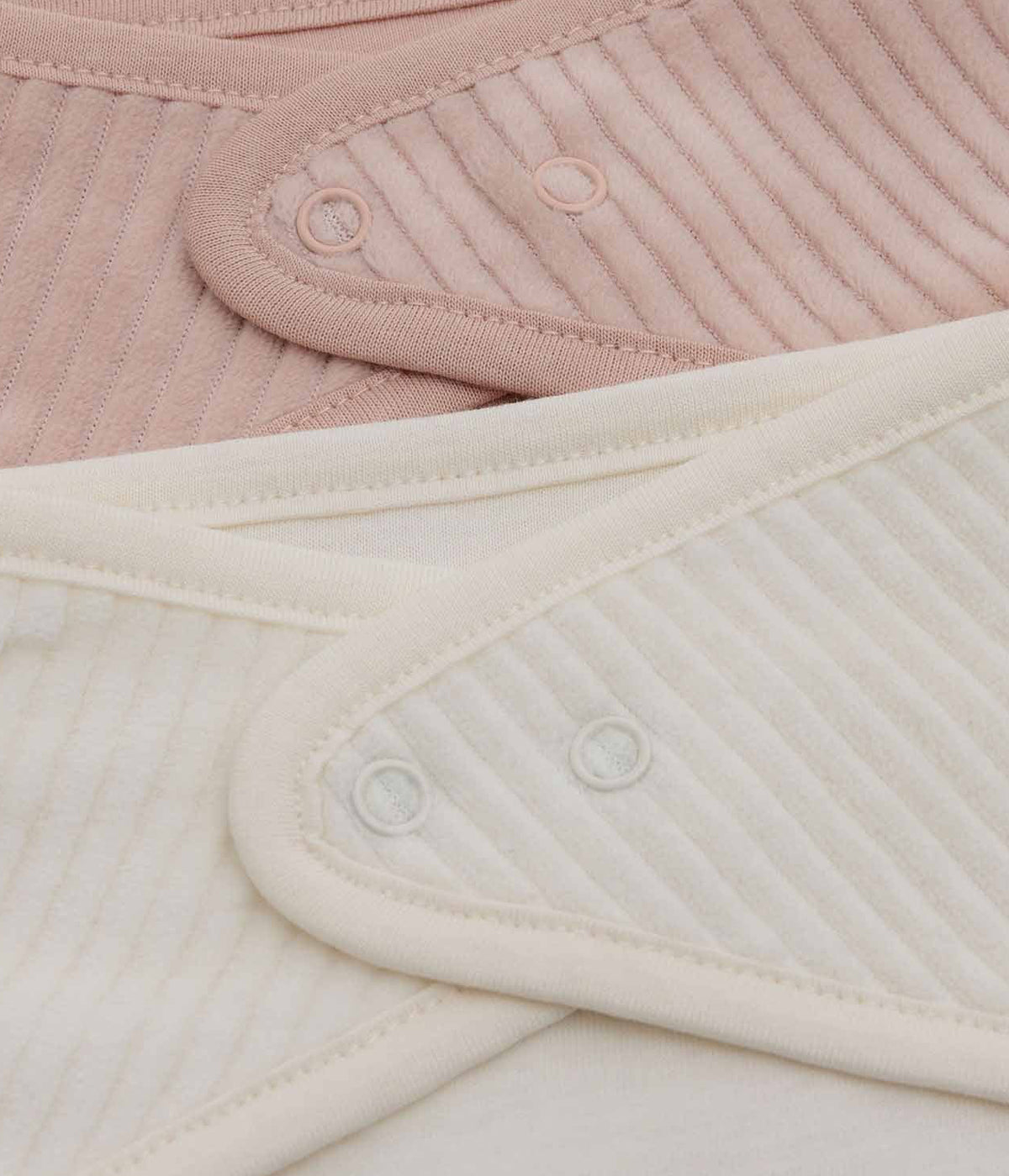 Conjunto de duas babetes em veludo canelado da Jollein para bebé menina e recém-nascida. Suaves babetes, uma pérola e outra rosa, perfeitas para manter a bebé limpa enquanto aprende a beber e comer sozinha.