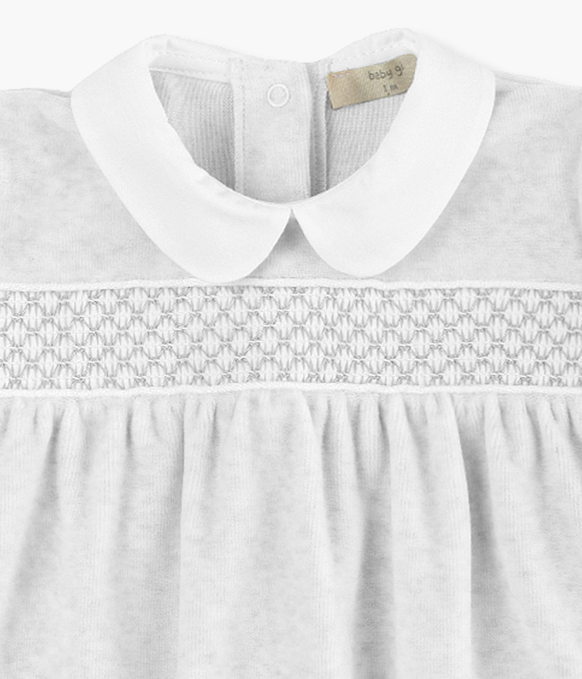 Babygrow em veludo cinza da Baby Gi para bebé e recém-nascido(a). Gola redonda cortada e faixa com favos na frente. Abertura com molas de pressão nas costas e entrepernas.