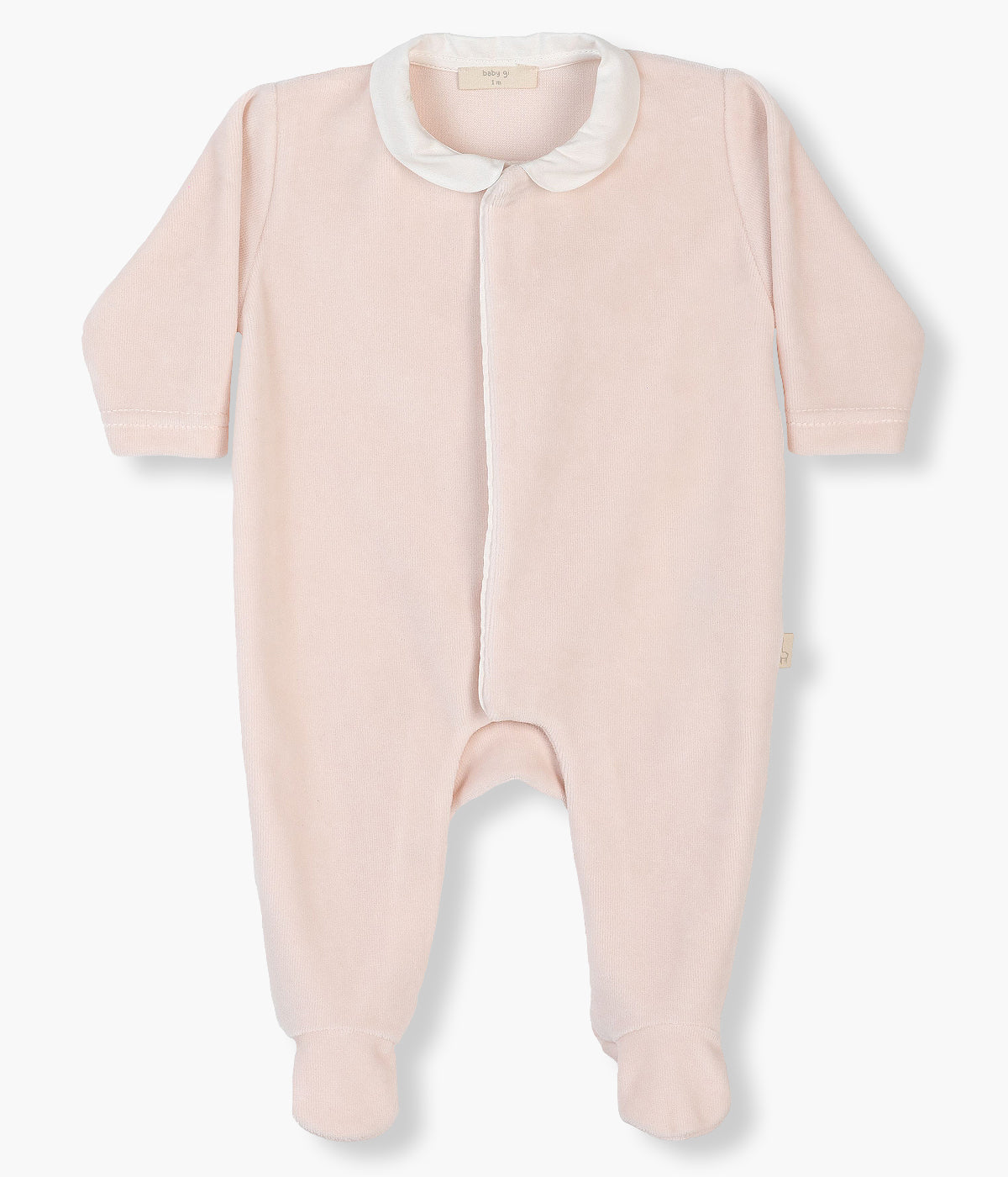 Babygrow em veludo nude da Baby Gi para bebé menina e recém-nascida. Gola redonda cortada e detalhe de asas de anjo nas costas em branco. Abertura com molas de pressão na frente e entrepernas.