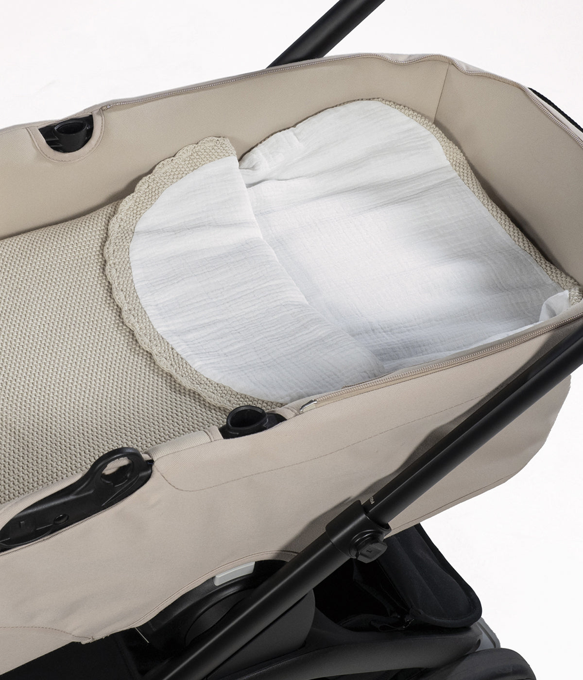 Saco manta em malha de algodão tricot bege da Pasito a Pasito para bebé e recém-nascido(a). Este suave saco manta destaca-se pelo seu ponto de arroz requintado e um elegante acabamento com rebordo ondulado. Possui um design funcional com um interior em tecido musselina branco, permitindo ser utilizado como ninho ou como manta de berço, acompanhando o crescimento e as diferentes necessidades do bebé.
