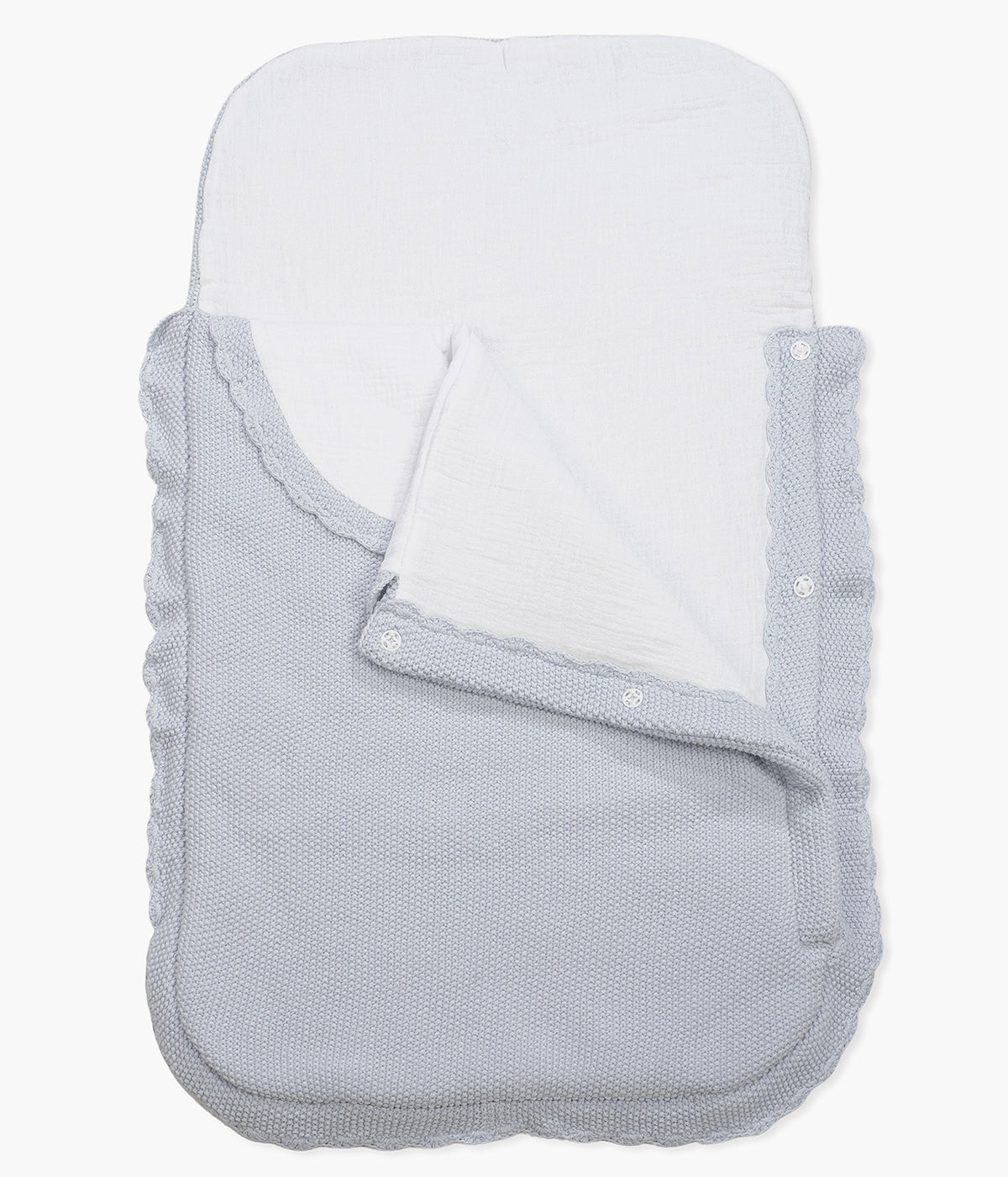 Saco manta em malha de algodão tricot azul da Pasito a Pasito para bebé menino. Este suave saco manta destaca-se pelo seu ponto de arroz requintado e um elegante acabamento com rebordo ondulado. Possui um design funcional com um interior em tecido musselina branco, permitindo ser utilizado como ninho ou como manta de berço, acompanhando o crescimento e as diferentes necessidades do bebé.