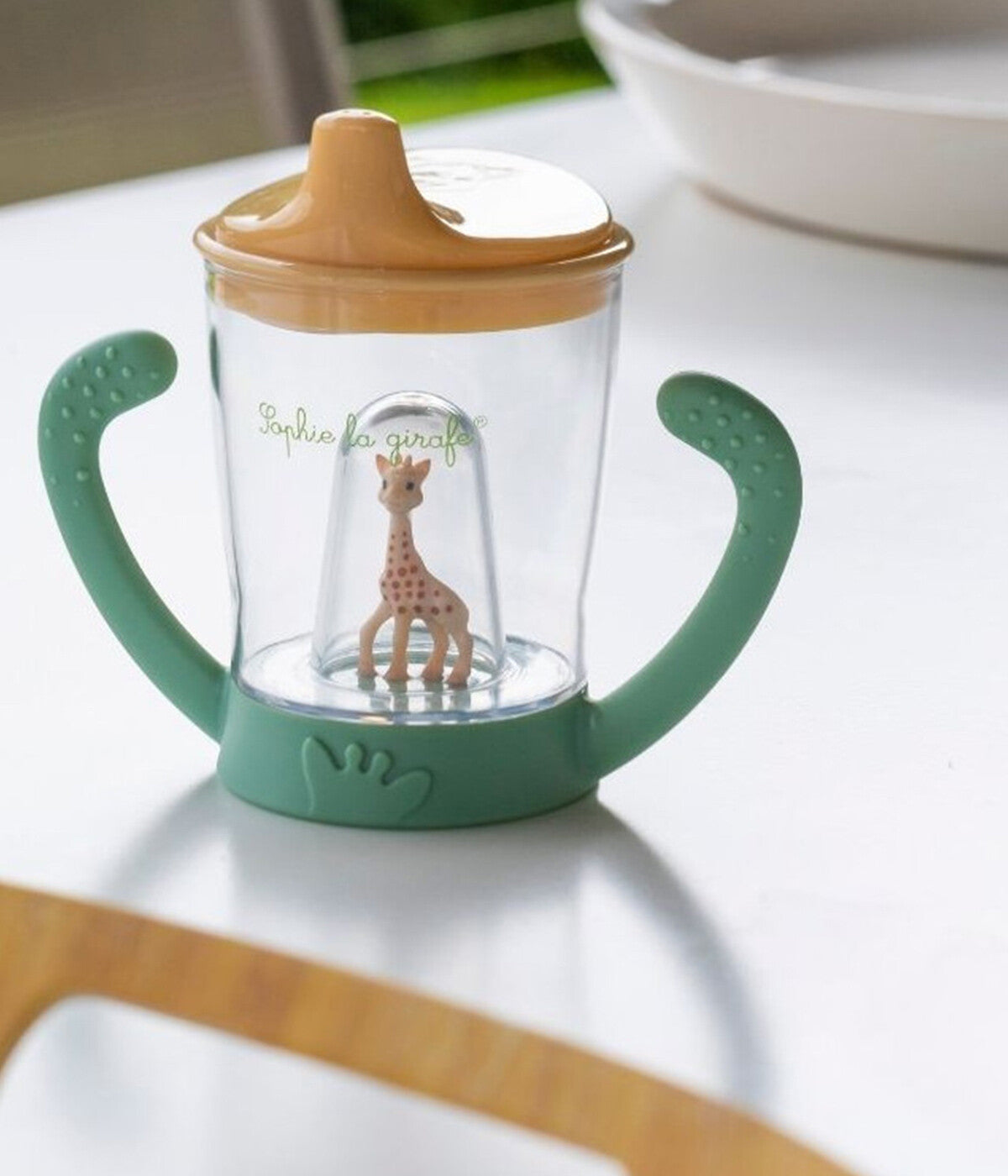 Copo anti-vazamento Sophie La Girafe com sistema de válvula que permite ao bebé beber sem entornar. O seu bico ergonómico permite uma sucção natural comparável à forma de beber do biberão. Ideal para a transição do biberão para o copo.