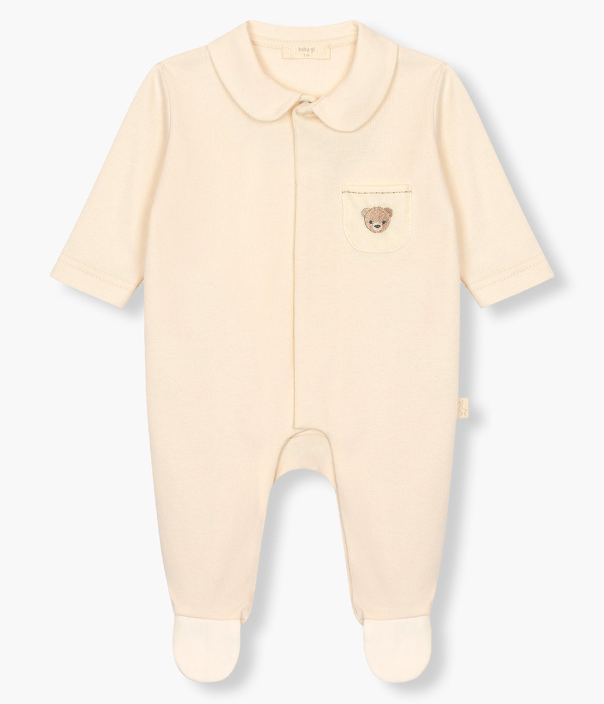 Vista de frente do babygrow em algodão bege da Baby Gi para bebé e recém-nascido. Gola redonda cortada e bolso no peito com urso bordado em castanho. Abertura com molas de pressão na frente e entrepernas.