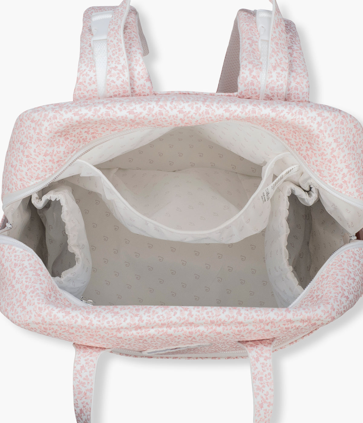Vista do interior da mochila de maternidade Maison Tender Flowers da Pasito a Pasito. Fabricada em pele vegana com tratamento resistente à água, esta mochila branca com padrão floral rosa oferece um interior espaçoso e bem organizado, com bolso térmico para biberão, bolso plastificado para roupa húmida e vários compartimentos para manter todos os essenciais facilmente acessíveis. Inclui ainda um resguardo portátil.