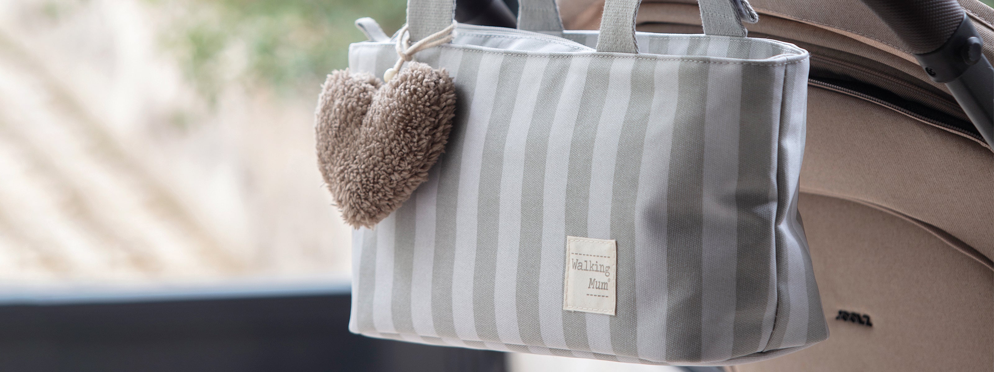 Bolsa de passeio da coleção Sintra da Walking Mum pendurada no carrinho de bebé com as alças.