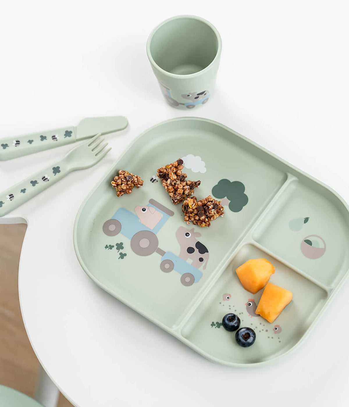 Conjunto de refeição em silicone de grau alimentar Done By Deer Tiny Farm verde composto por prato com ventosa, talheres ergonómicos e copo, ideal para as primeiras refeições do(a) bebé.