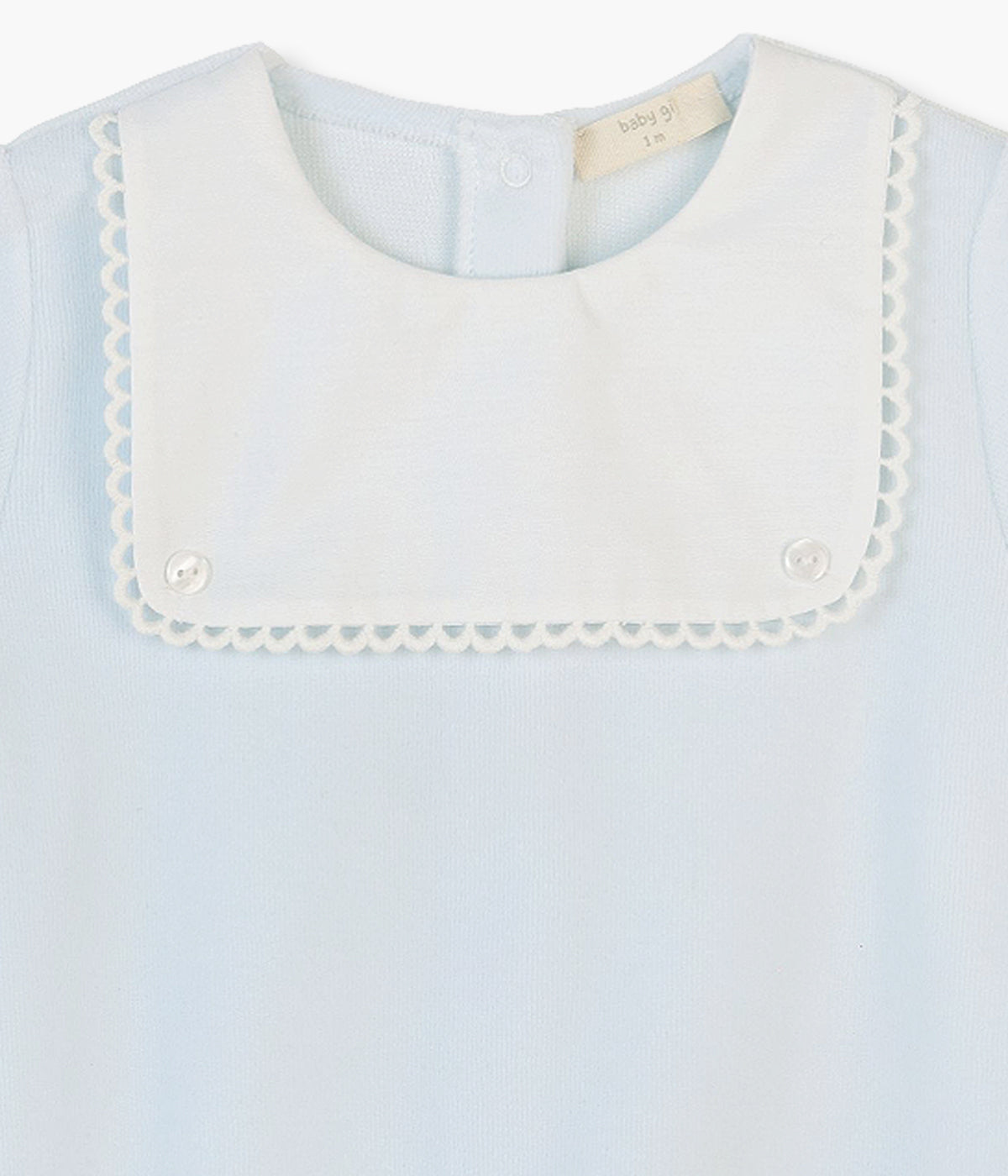 Babygrow em veludo azul da Baby Gi para bebé e recém-nascido(a). Detalhe de peitilho e tecido branco com dois botões decorativos. Abertura com molas de pressão nas costas e entrepernas.