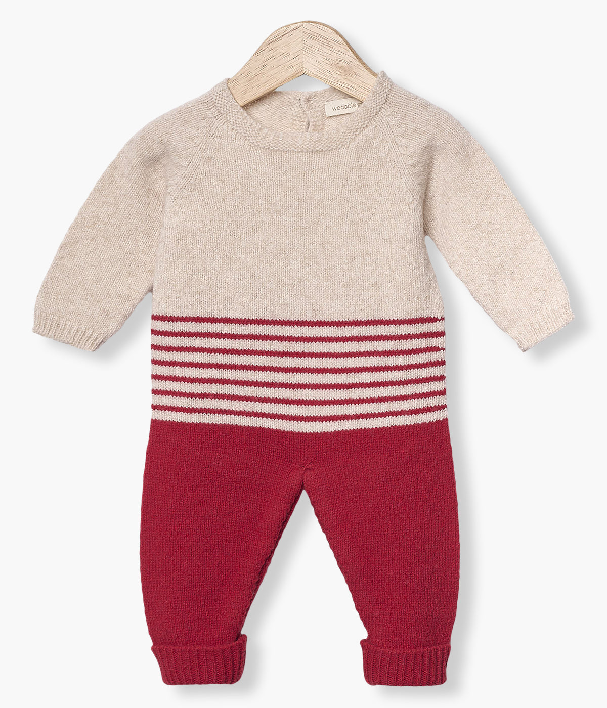 Babygrow tricotado em lã merino da Wedoble para bebé e recém-nascido(a). Parte superior em bege e parte inferior com riscas em vermelho. Abertura nas costas com botões de madeira e entrepernas com molas de pressão para vestir facilmente.