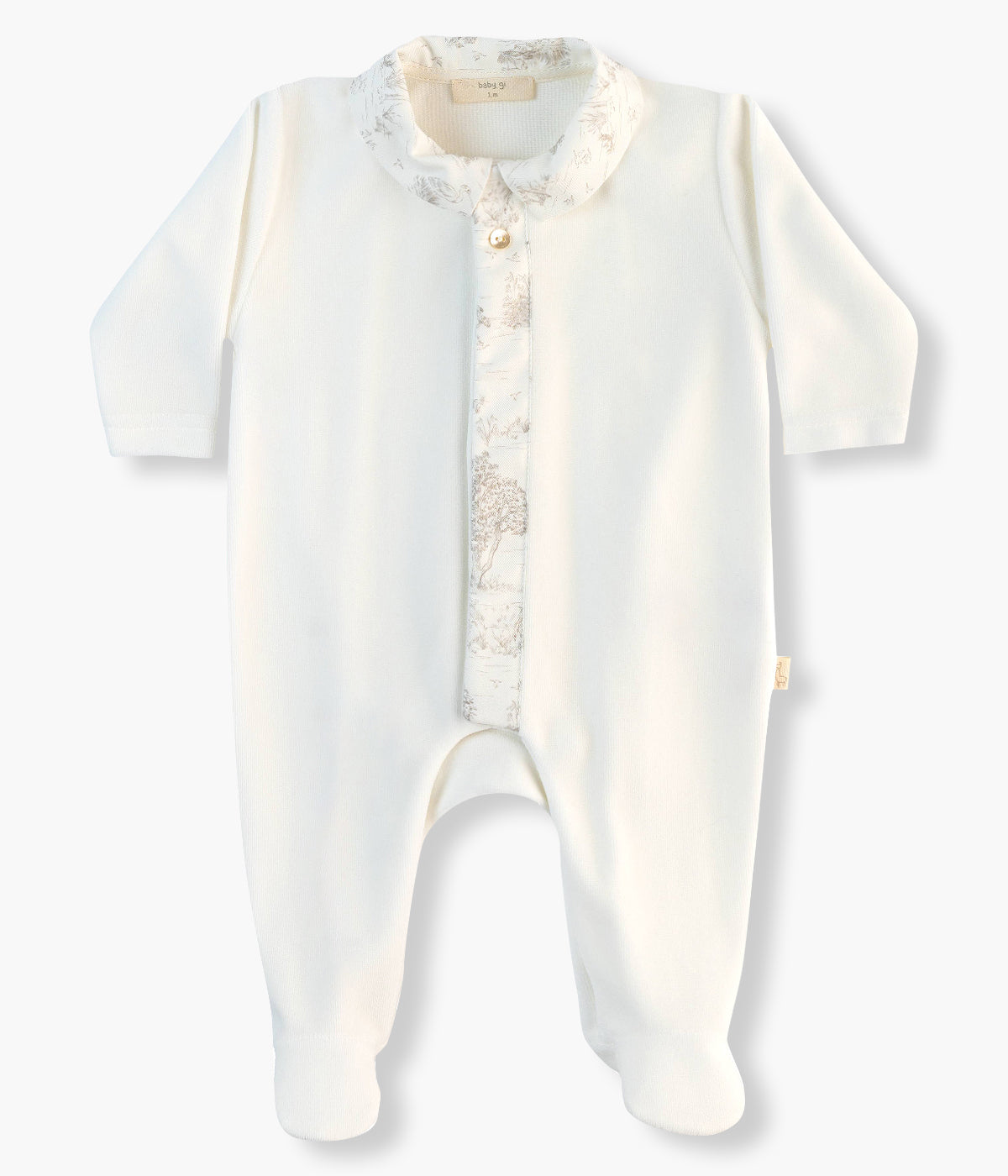 Babygrow em veludo pérola da Baby Gi para bebé e recém-nascido(a). Gola bico cortada e faixa na abertura com padrão&nbsp;toile de jouy e um botão decorativo madrepérola no peito. Abertura com molas de pressão na frente e entrepernas.