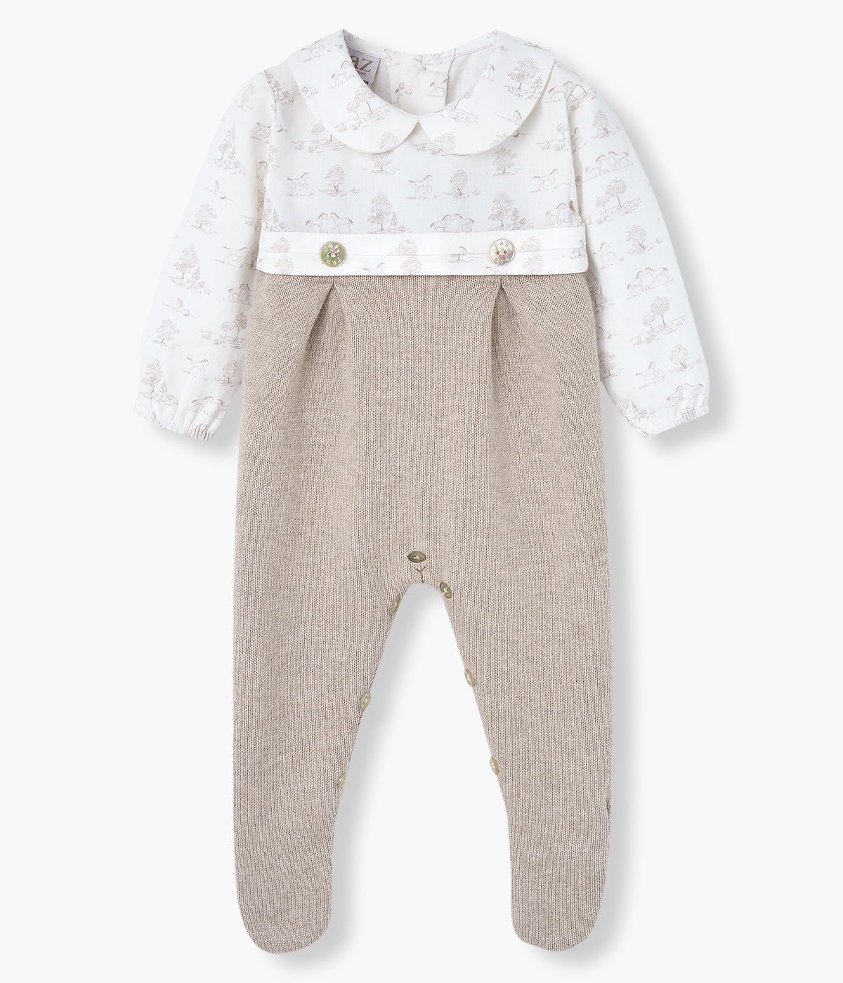 Babygrow em malha de algodão com caxemira bege da Paz Rodríguez para bebé e recém-nascido(a). Parte superior em algodão com gola redonda cortada, padrão toile de jouy em tons de bege com fundo branco e dois botões madrepérola decorativos. Parte inferior em malha.