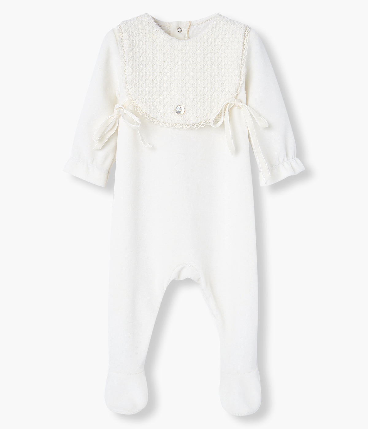 Babygrow em veludo pérola da Paz Rodríguez para bebé e recém-nascido(a). Elegante babygrow com peitilho com tecido texturado e renda, dois laços nas laterais e medalha madrepérola com logo da marca.
