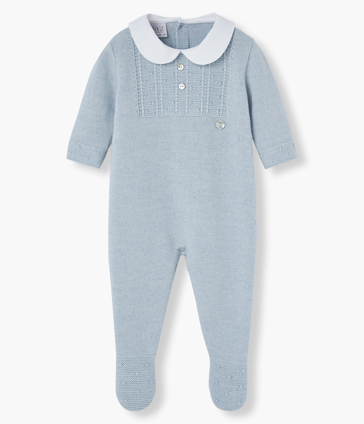 Babygrow em malha azul da Paz Rodríguez para bebé e recém-nascido(a). Elegante babygrow com gola redonda cortada branca, detalhes na malha no peito e nos pés e medalha da marca.