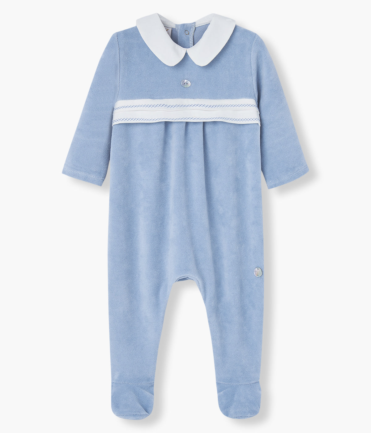 Babygrow em veludo azul-escuro da Paz Rodríguez para bebé menino e recém-nascido. Elegante babygrow com gola redonda cortada branca, detalhe no peito com bordado à cor e medalha madrepérola da marca.