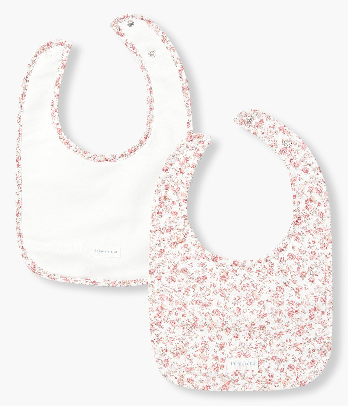 Pack de 2 babetes com turco impermeável da Laranjinha para bebé menina e recém-nascida. Uma babete com contorno a toda a volta e outra totalmente estampada com padrão floral em tons de rosa.