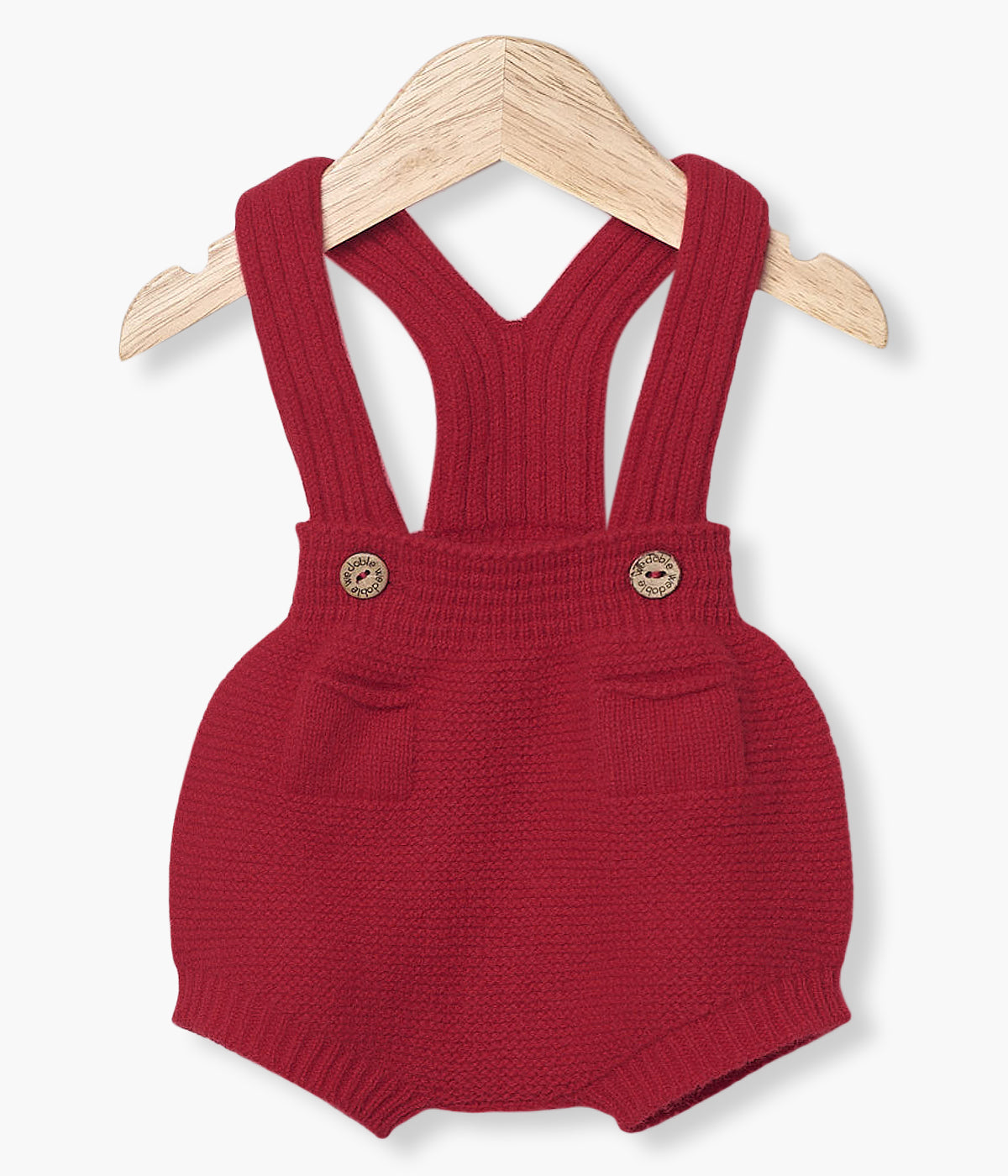 Fofo tricotado em lã merino vermelho da Wedoble para bebé e recém-nascido(a). Delicado fofo com dois bolsos decorativos na frente e abertura nas alças com botões de madeira.