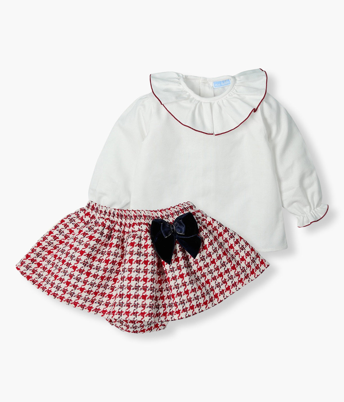 Conjunto composto por blusa e tapa fraldas da Mac Ilusión para bebé menina e recém-nascida. Blusa em algodão com gola folho e punhos com contorno em bordô. Tapa fraldas com folho padrão pied-de-poule vermelho e branco e laço azul-marinho com contornos em dourado. 