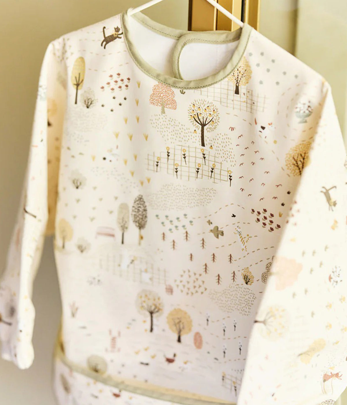 Babete impermeável com mangas pérola e verde com padrão animais e árvores Tiny Park da Jollein para bebé. Babete com mangas e bolso perfeita para o bebé utilizar nas refeições ou em outras atividades. Graças ao fecho em velcro, esta babete adapta-se tanto a bebés como a crianças pequenas.