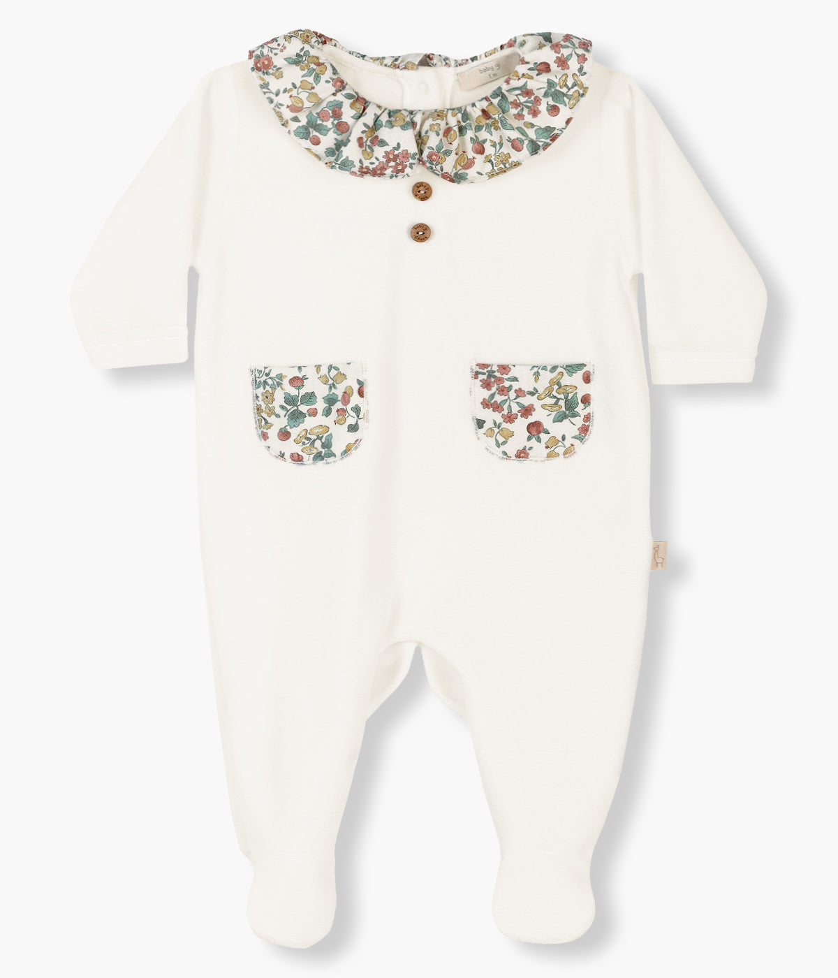 Babygrow em veludo pérola da Baby Gi para bebé menina e recém-nascida. Gola folho cortada e dois bolsos com aplicação em tecido de padrão floral. Dois botões decorativos no peito. Abertura nas costas e entrepernas.