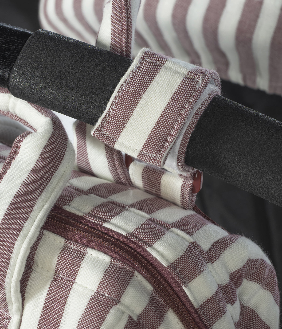 Mochila de maternidade Cherry Strips da Pasito a Pasito pendurada num carrinho de bebé.